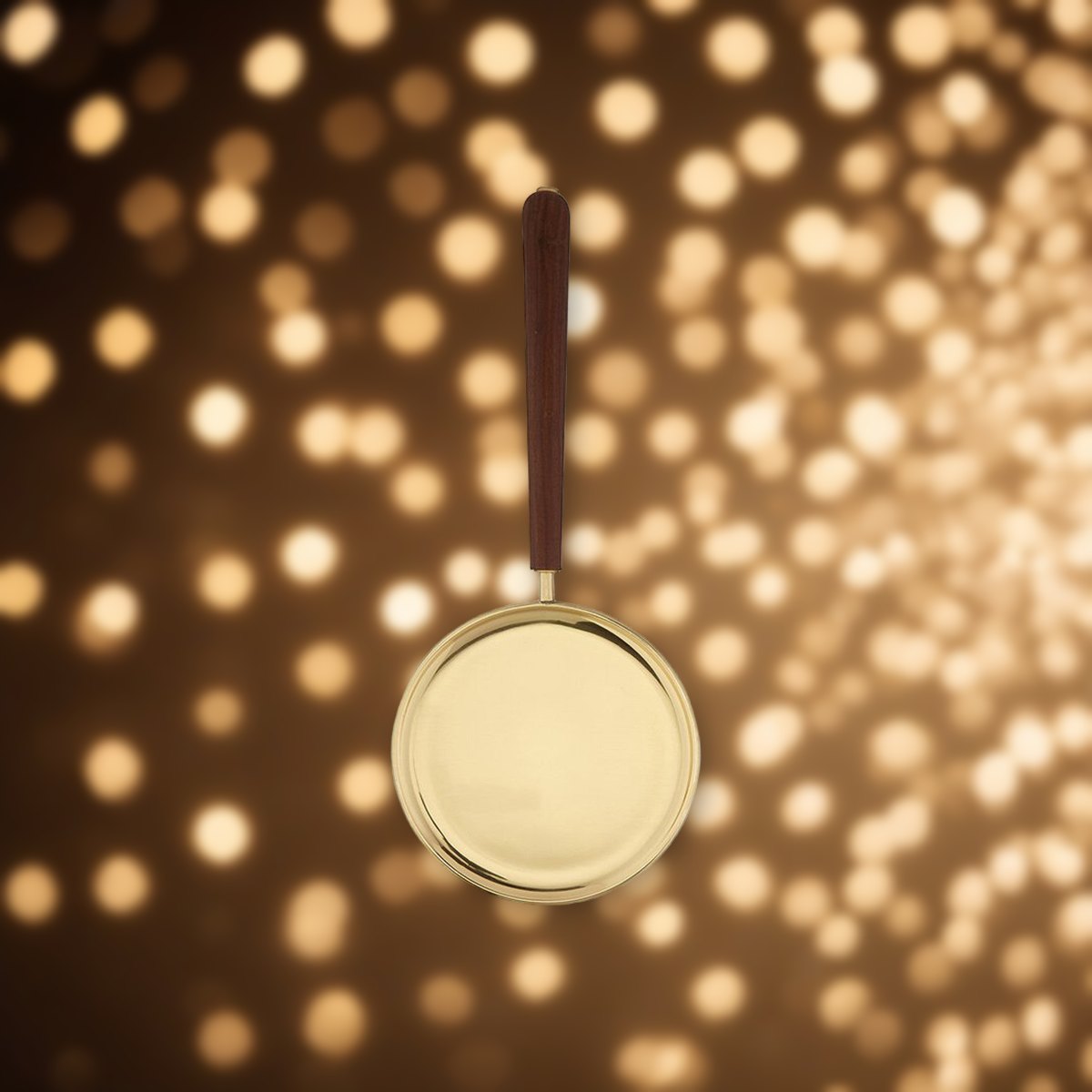 Brass Paten with Straight Handle against soft golden light