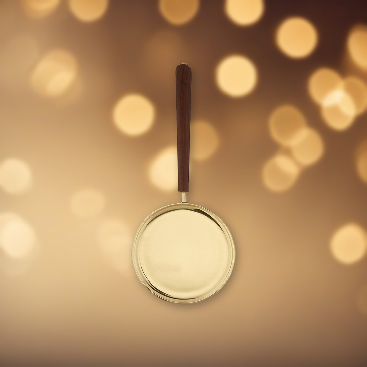 Brass Paten with Straight Handle against soft golden light