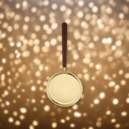 Brass Paten with Straight Handle against soft golden light