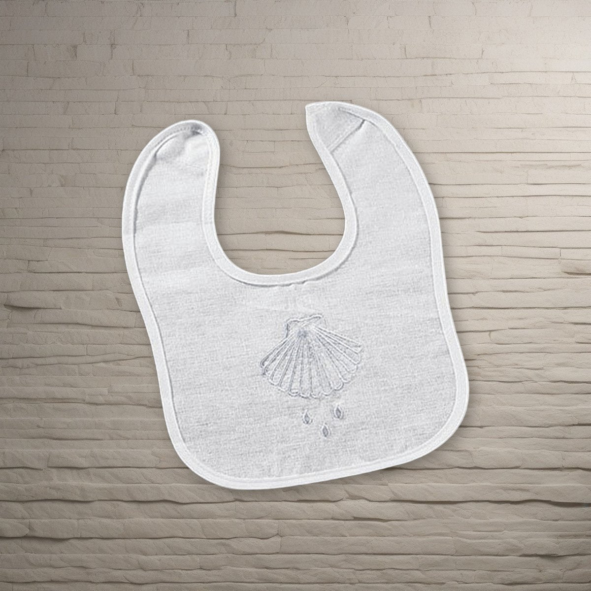 Shell & Water Embroidered Baptismal Bib 12/pk on a stone background